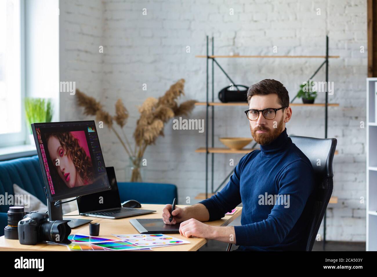 Retusche Bilder in speziellen Programm.Portrait von Grafikdesigner arbeiten im Büro mit Laptop, Monitor, Grafik Zeichnung Tablette und Farbpalette Stockfoto