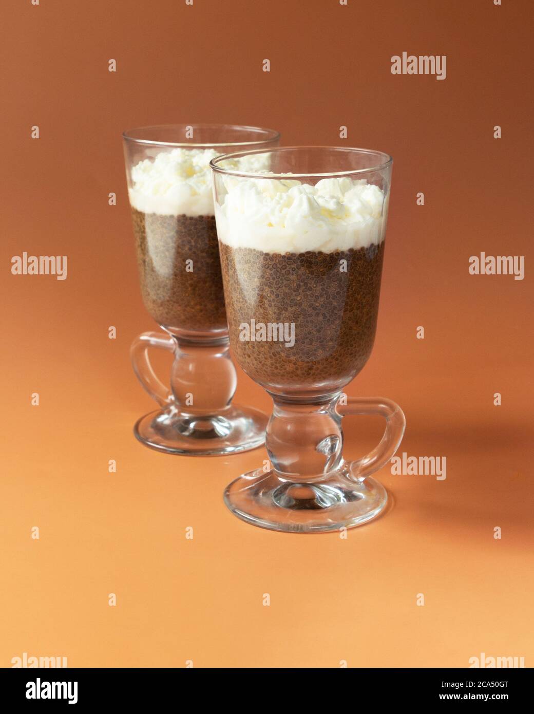 Kaffee Chia Pudding in Glas auf braun - orange Hintergrund. Stockfoto