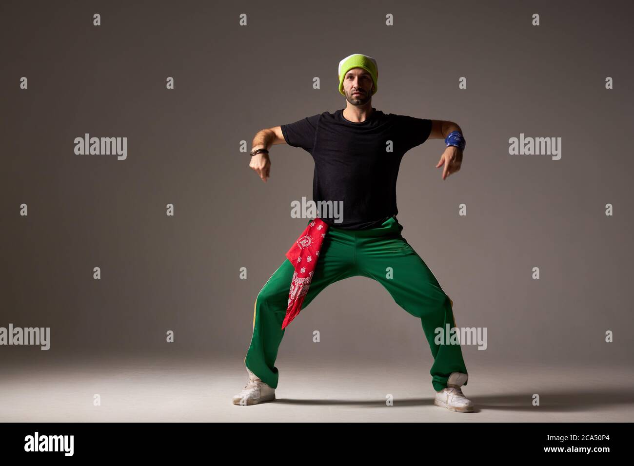 Attraktive professionelle Tänzerin, die modernen Hip-Hop-Stil Tanz, Strecken Hände und Beine seitwärts, Blick auf die Kamera mit brutalem Gesicht, zeigt Stockfoto