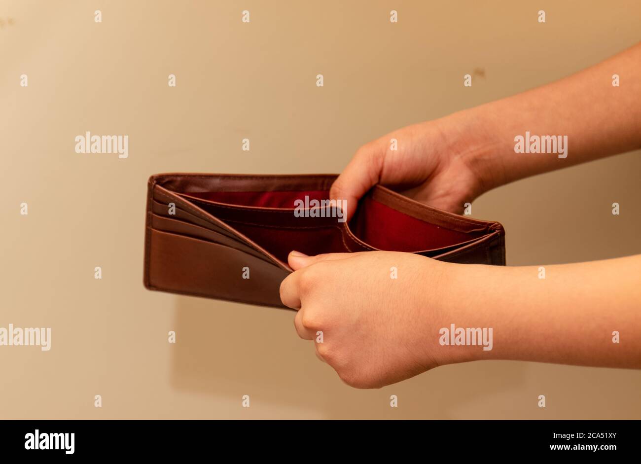 Crop-Ansicht von Young man Hände Überprüfung leere braune Brieftasche. Aufgrund der Verlangsamung der Weltwirtschaft überleben die Menschen für Geld. Stockfoto