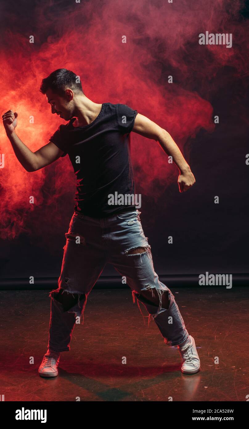 Schöner Mann, der isoliert auf rauchigem Hintergrund tanzt, Freizeitkleidung trägt, Straßentanz Stockfoto