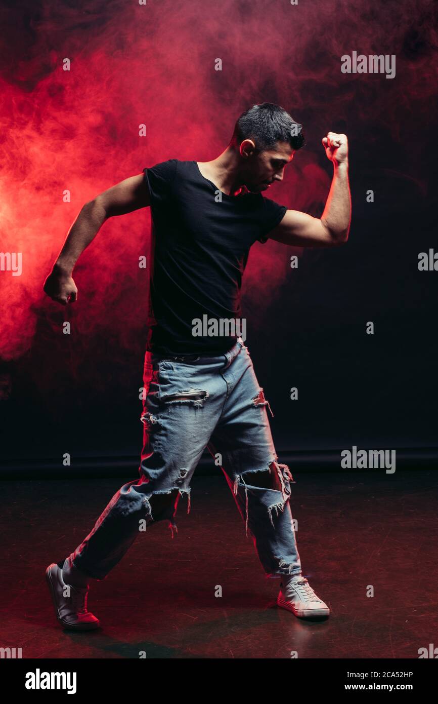 Junge kräftige männliche Tanz isoliert über rot rauchigen Raum, tragen Casual Wear. Street Dance Konzept Stockfoto