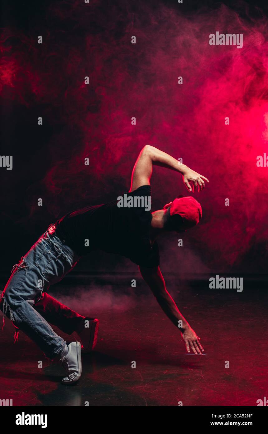 Schöner Mann, der isoliert auf rauchigem Hintergrund tanzt, Freizeitkleidung trägt, Straßentanz Stockfoto