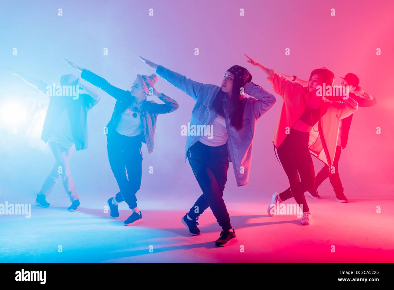 Gruppe von verschiedenen jungen Hip-Hop-Tänzern im Studio mit speziellen Lichteffekten in blauen und rosa Farben Stockfoto