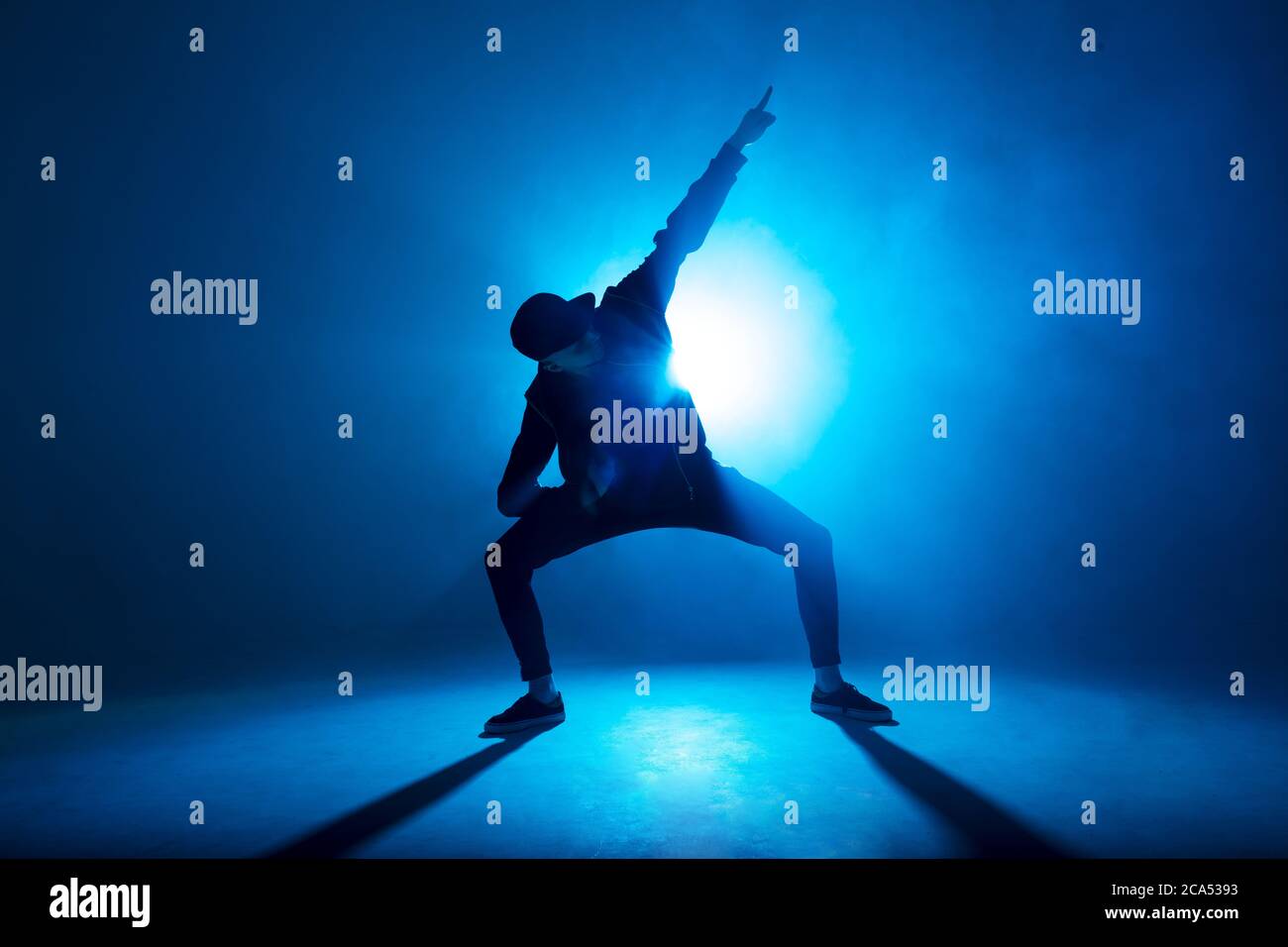 Full-Size-Silhouette der männlichen Pause Tänzer auf blauen Neon Bühne seine expressive Tanz, dunkelblauen Hintergrund mit Licht Flare auf dem Hintergrund Stockfoto