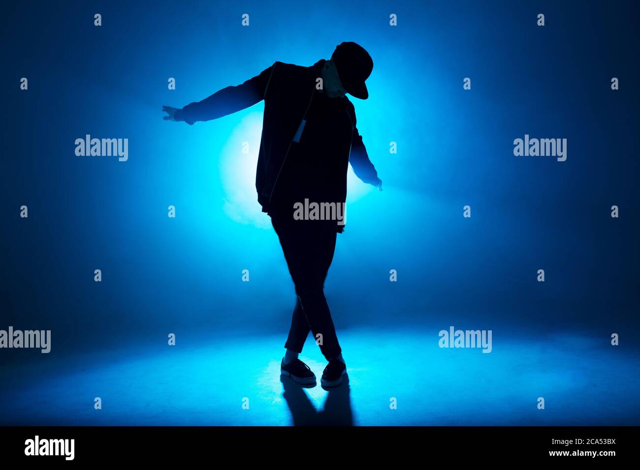 Silhouette eines Mannes, der Solo-Performance gibt, allein im Hip-Hop-Stil in der Clubszene tanzt, mit blauem Neon-Blitz und Rauch. Stockfoto