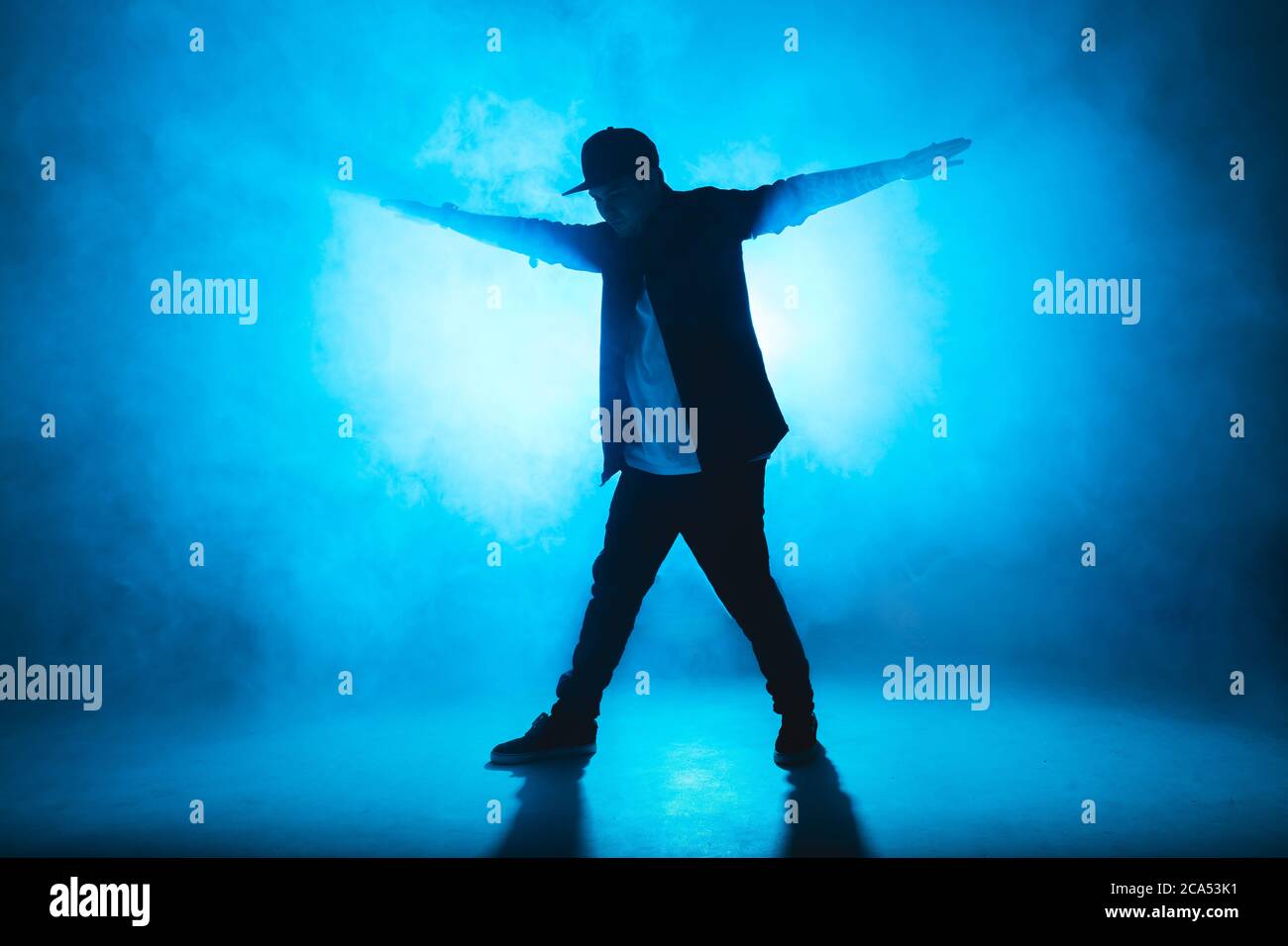Full-Size-Silhouette der männlichen Pause Tänzer auf blauen Neon Bühne seine expressive Tanz, dunkelblauen Hintergrund mit Licht Flare auf dem Hintergrund Stockfoto