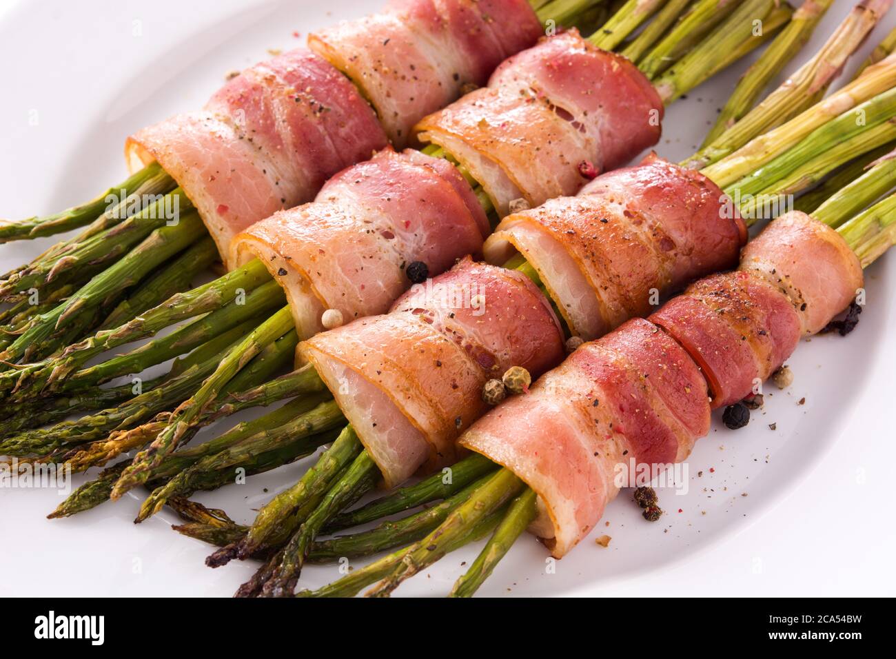 Grüner Spargel mit Speck isoliert auf weißem Hintergrund eingewickelt.Nahaufnahme Stockfoto