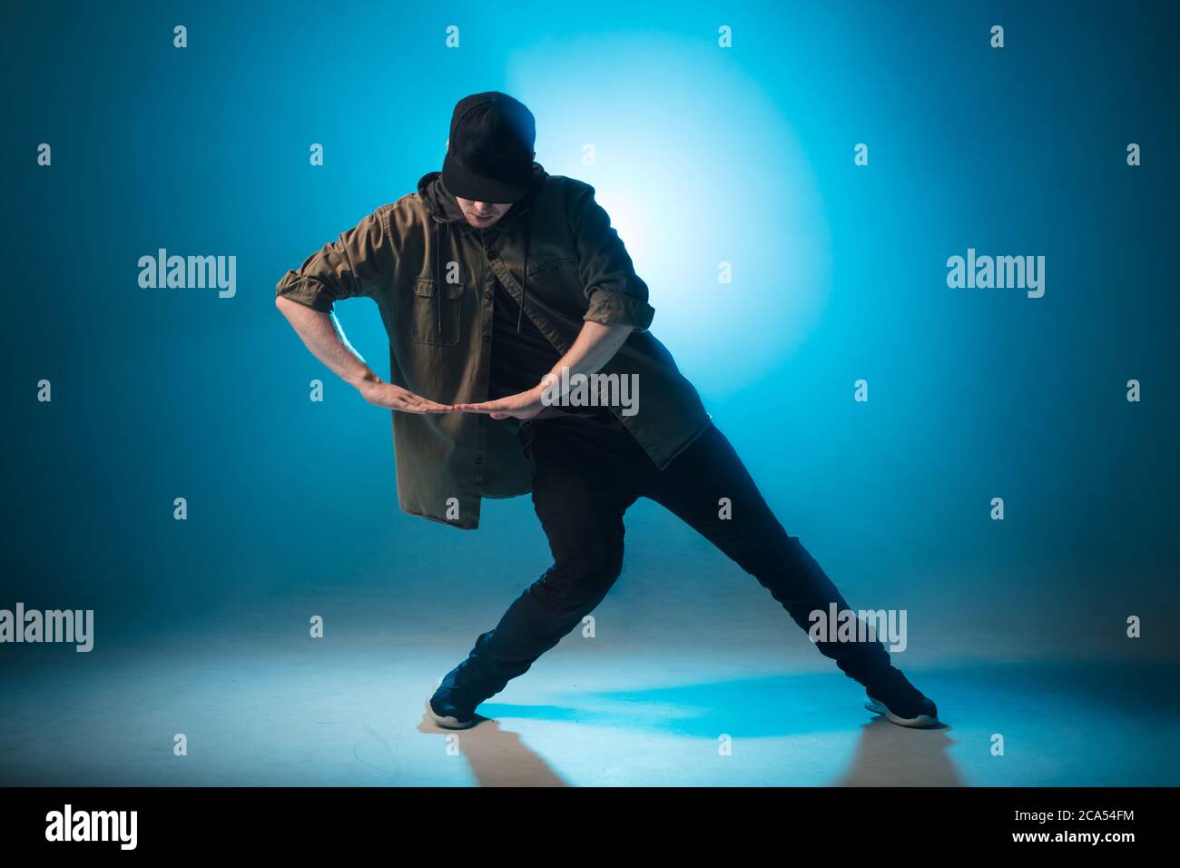 Full-Size-Silhouette der männlichen Pause Tänzer auf blauen Neon Bühne seine expressive Tanz, dunkelblauen Hintergrund mit Licht Flare auf dem Hintergrund Stockfoto