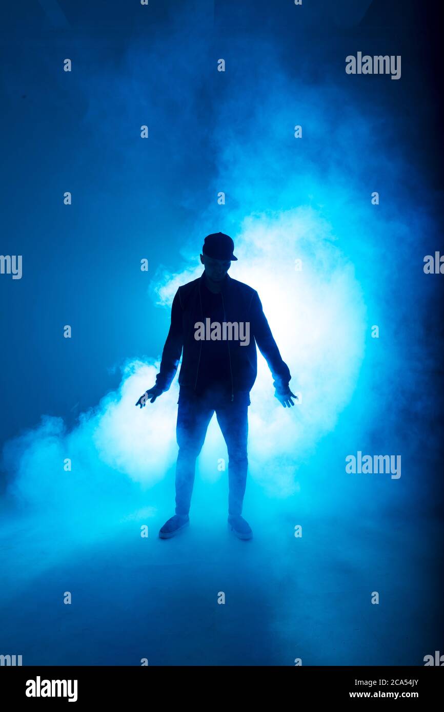 Silhouette eines Mannes, der Solo-Performance gibt, allein im Hip-Hop-Stil in der Clubszene tanzt, mit blauem Neon-Blitz und Rauch. Stockfoto