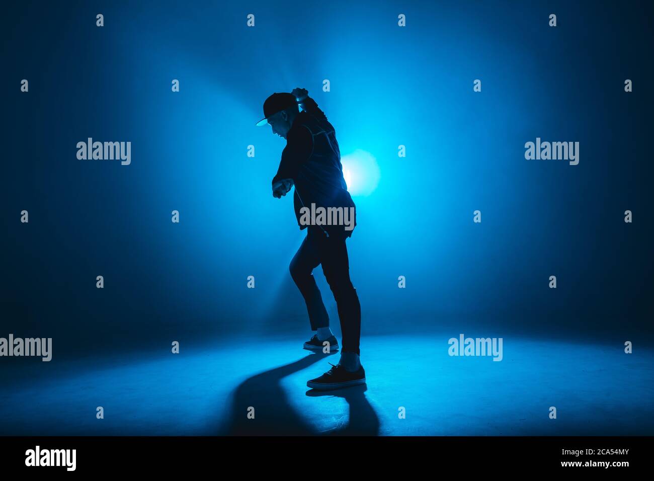 Silhouette eines Mannes, der Solo-Performance gibt, allein im Hip-Hop-Stil in der Clubszene tanzt, mit blauem Neon-Blitz und Rauch. Stockfoto