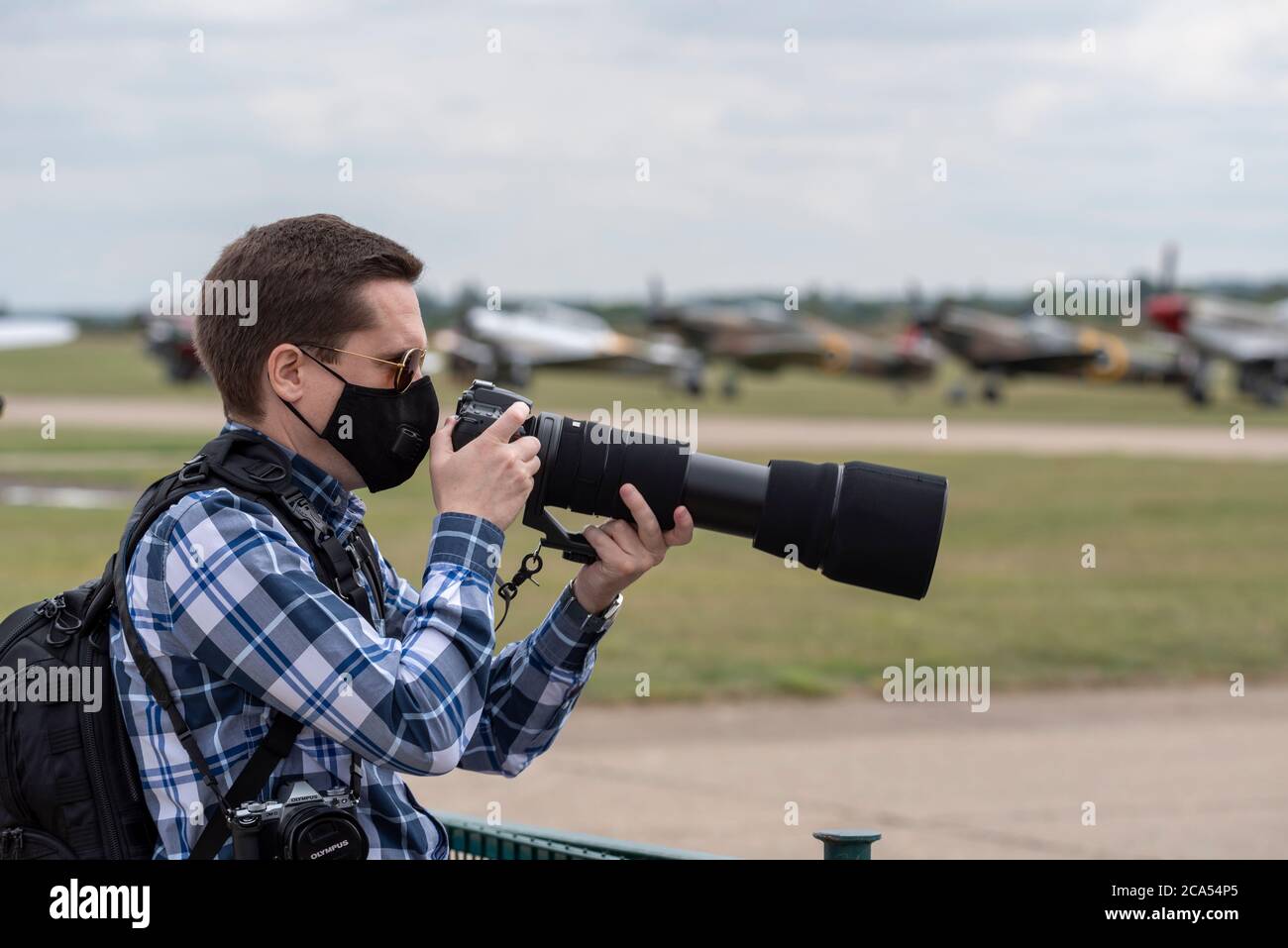 Imperial war Museum Duxford, Cambridgeshire, Großbritannien. August 2020. Nach einer langen Stilllegung durch die COVID-19 Coronavirus-Sperre öffnete das Museum am 1. August wieder seine Türen für Besucher. Heute hat das Museum seine erste Luftvorstellungsveranstaltung abgehalten – mit dem Titel A Showcase Day. Es war eine vorab gebuchte Ticket-only-Veranstaltung mit stark reduziertem Besucherlimit, und die Besucher mussten strenge Richtlinien einhalten, wenn sie die Innenausstattungen betraten. Ein Fotograf mit Weitwinkelobjektiv und Gesichtsmaske Stockfoto