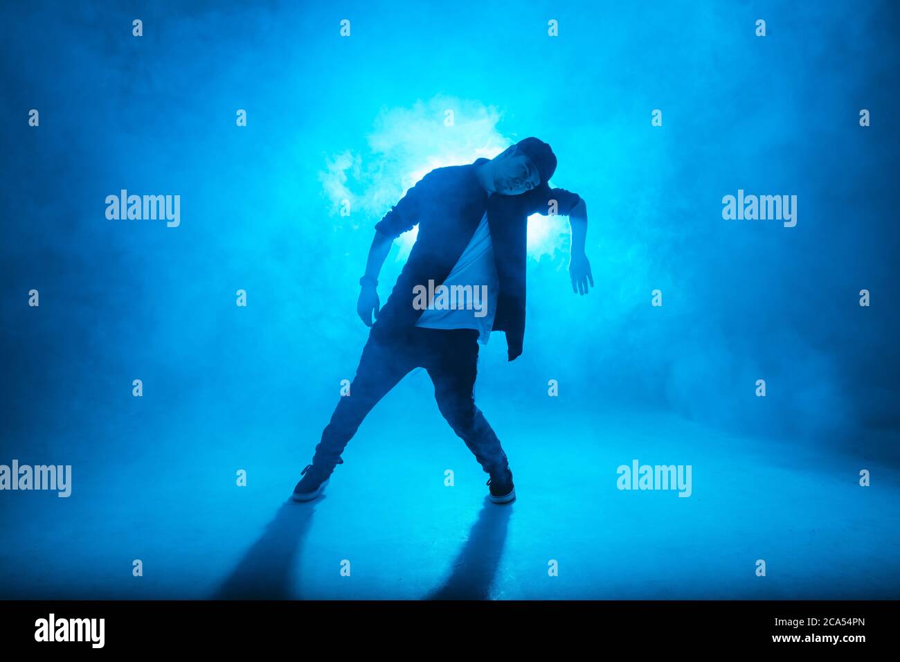 Full-Size-Silhouette der männlichen Pause Tänzer auf blauen Neon Bühne seine expressive Tanz, dunkelblauen Hintergrund mit Licht Flare auf dem Hintergrund Stockfoto