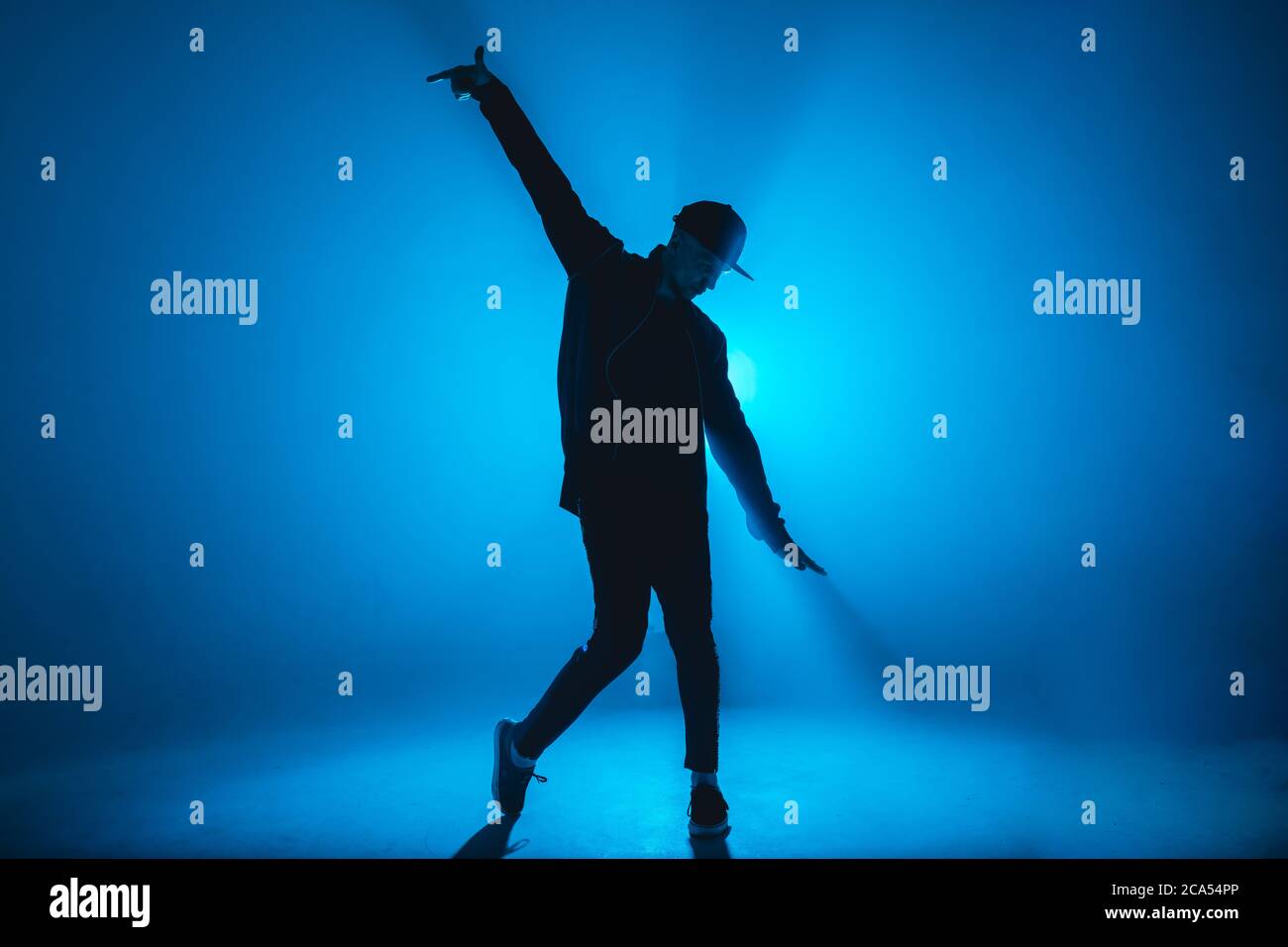Full-Size-Silhouette der männlichen Pause Tänzer auf blauen Neon Bühne seine expressive Tanz, dunkelblauen Hintergrund mit Licht Flare auf dem Hintergrund Stockfoto