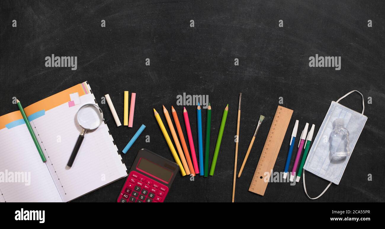 Schulbedarf, Desinfektionsmittel und Maske auf der Tafel. Schulen im neuen Normalprozess öffnen Stockfoto