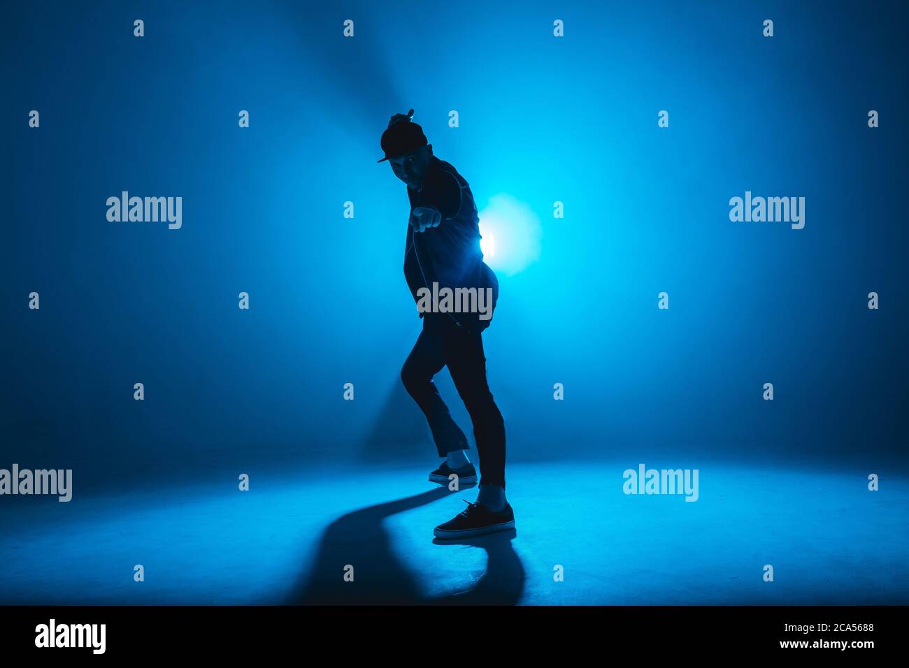 Full-Size-Silhouette der männlichen Pause Tänzer auf blauen Neon Bühne seine expressive Tanz, dunkelblauen Hintergrund mit Licht Flare auf dem Hintergrund Stockfoto