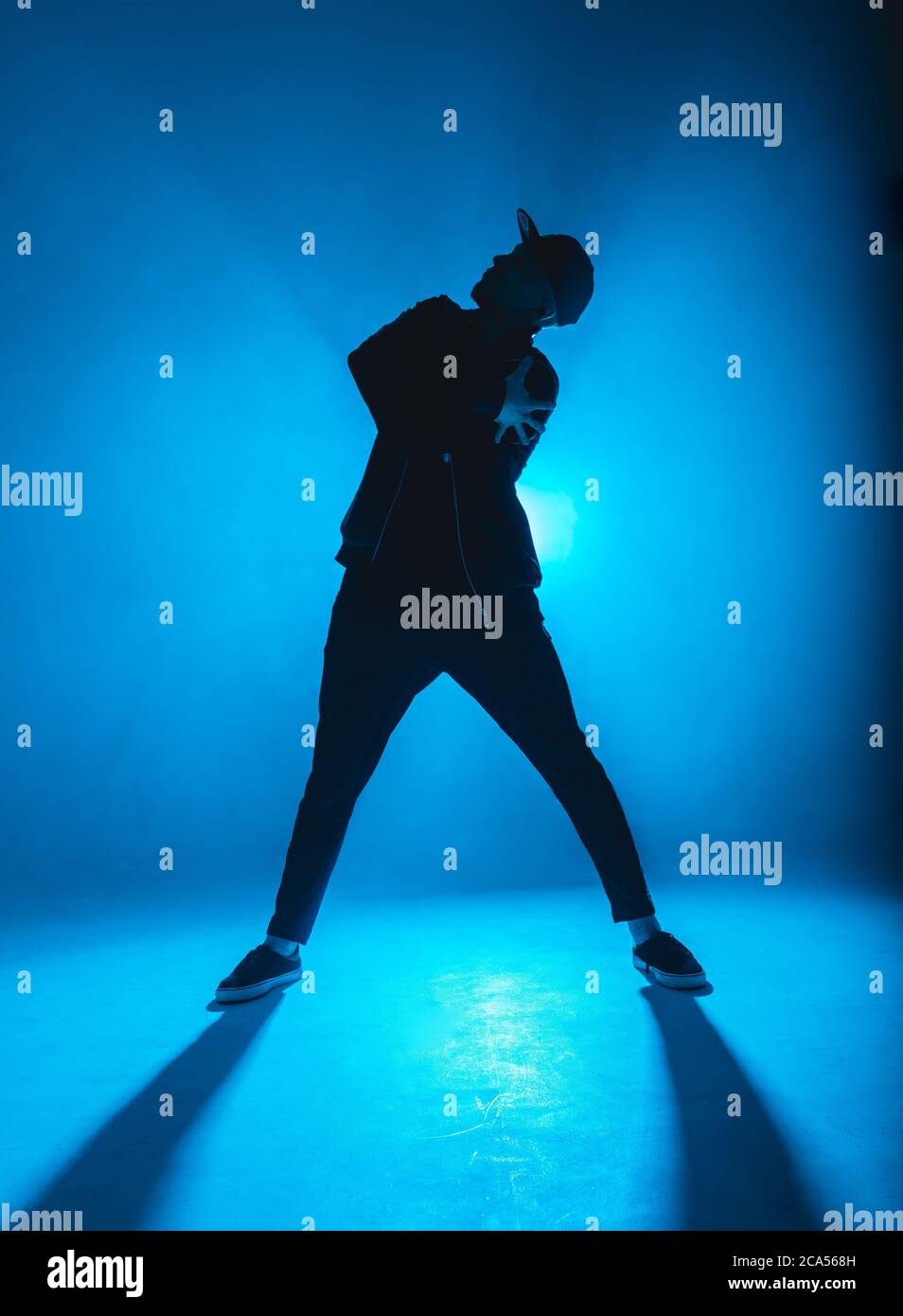 Silhouette eines Mannes, der Solo-Performance gibt, allein im Hip-Hop-Stil in der Clubszene tanzt, mit blauem Neon-Blitz und Rauch. Stockfoto
