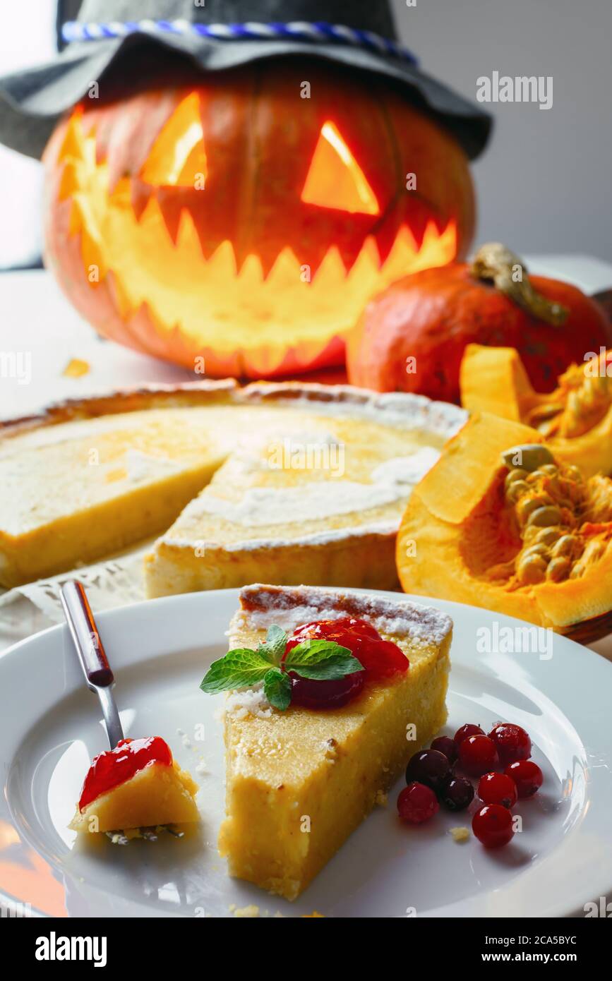 Stück süße hausgemachte halloween Kürbiskuchen mit Minzeblatt und Preiselbeermarmelade auf weißem Teller Nahaufnahme. Traditionelles Urlaubsessen Stockfoto