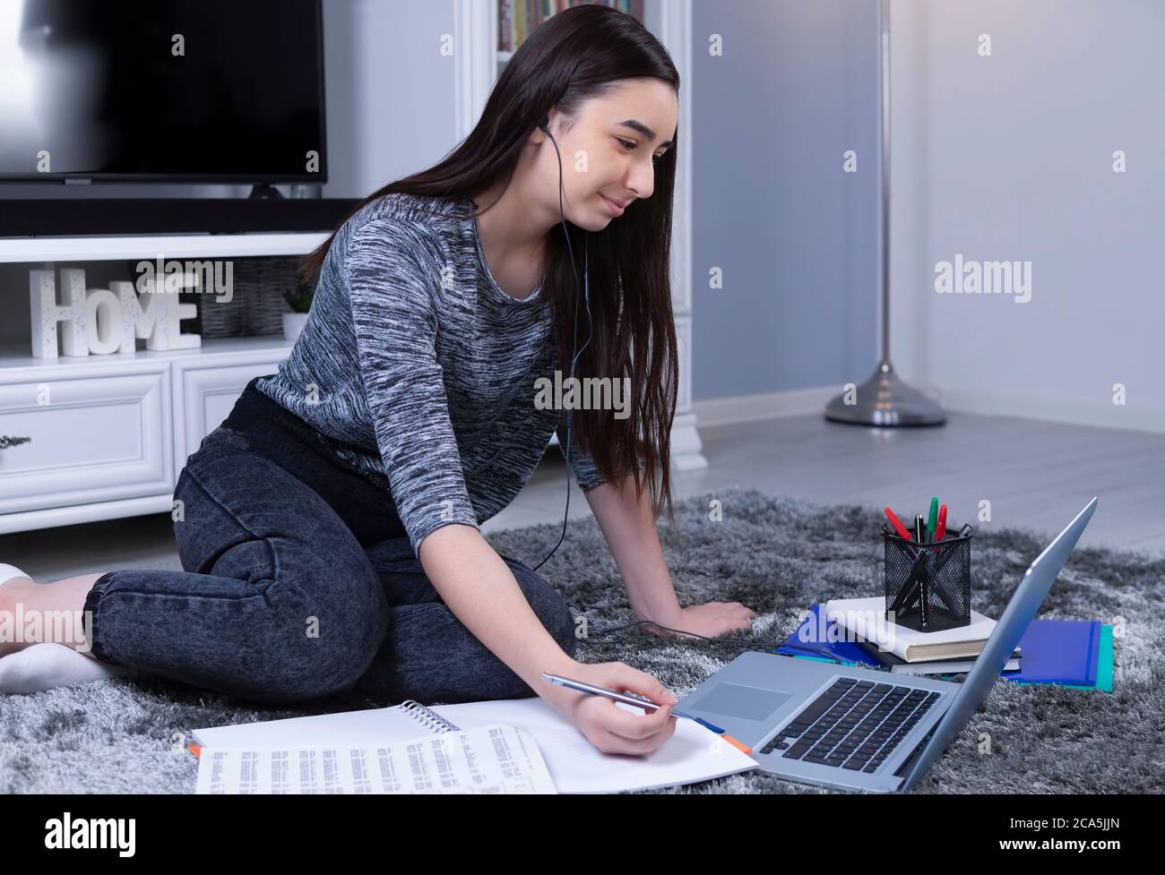 Studentin mit Laptop und Kopfhörer online zu Hause studieren. Bildungs- oder Freizeitkonzept. Stockfoto
