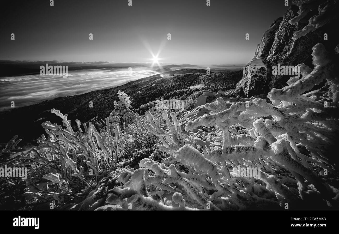 Sonnenaufgang und Inversion auf dem Jested Berg in der Nähe der Stadt Liberec, Tschechien, Schnee und Winter und Blick auf die Standseilbahn, Schneekorallen, schwarz und weiß. Stockfoto