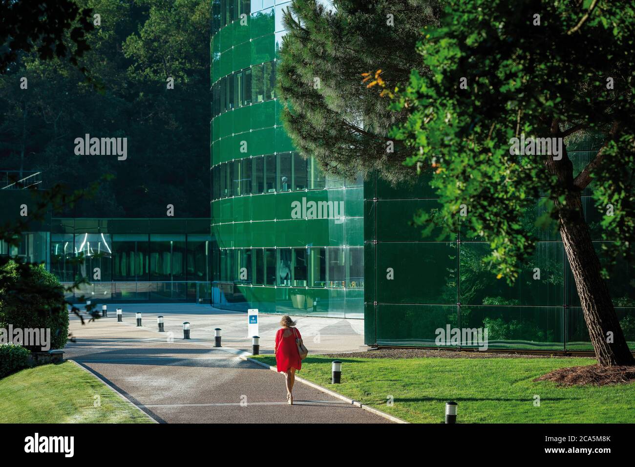 Frankreich, Tarn, Pierre Fabre Laboratories, Lavaur, Les Cauquillous, Mitarbeiter vor einem Gebäude der modernen und zeitgenössischen Architektur in Glas bei Sonnenaufgang in einer grünen Umgebung Stockfoto