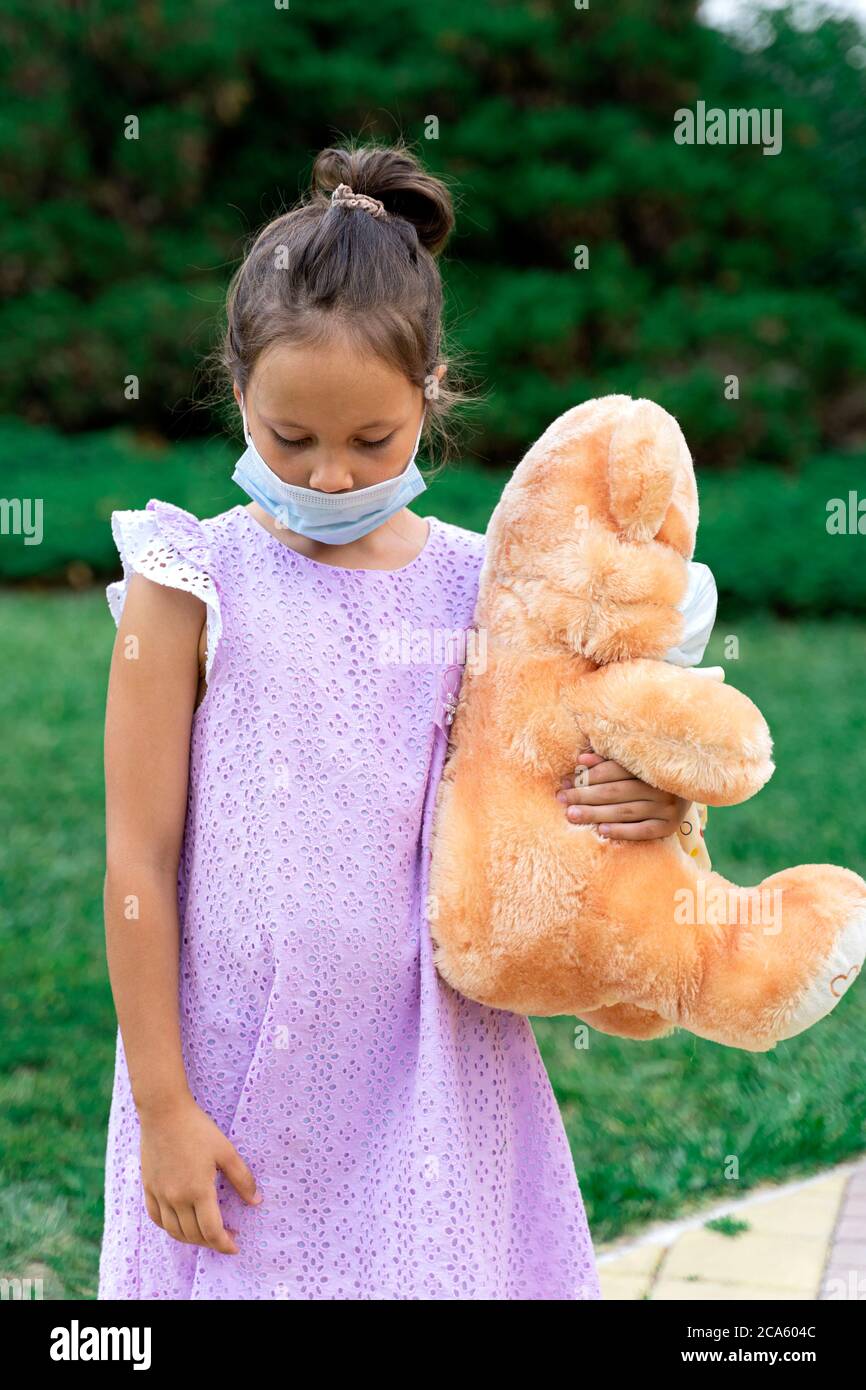 Ein kleines Mädchen in einer medizinischen Maske wartet auf Das Ende der Quarantäne und verfehlt ein normales Leben Stockfoto