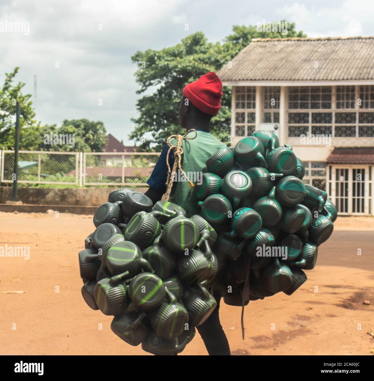 Afrikanischer Hausierer, der lokale Kessel verkauft, wurde auf der Straße in Kaduna an seinen Körper gebunden. Stockfoto