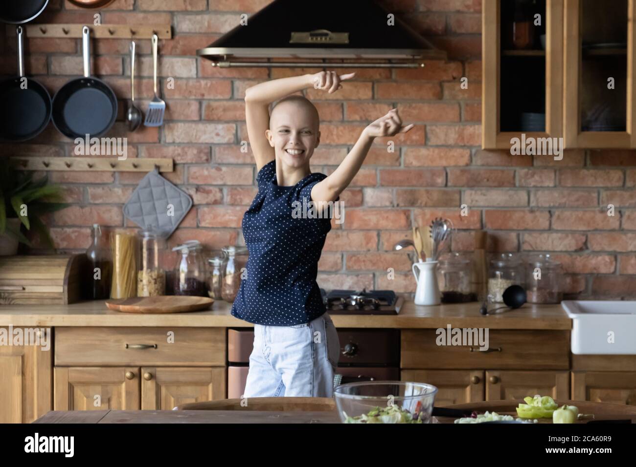 Glückliche junge kranke Frau, die in der heimischen Küche tanzt Stockfoto