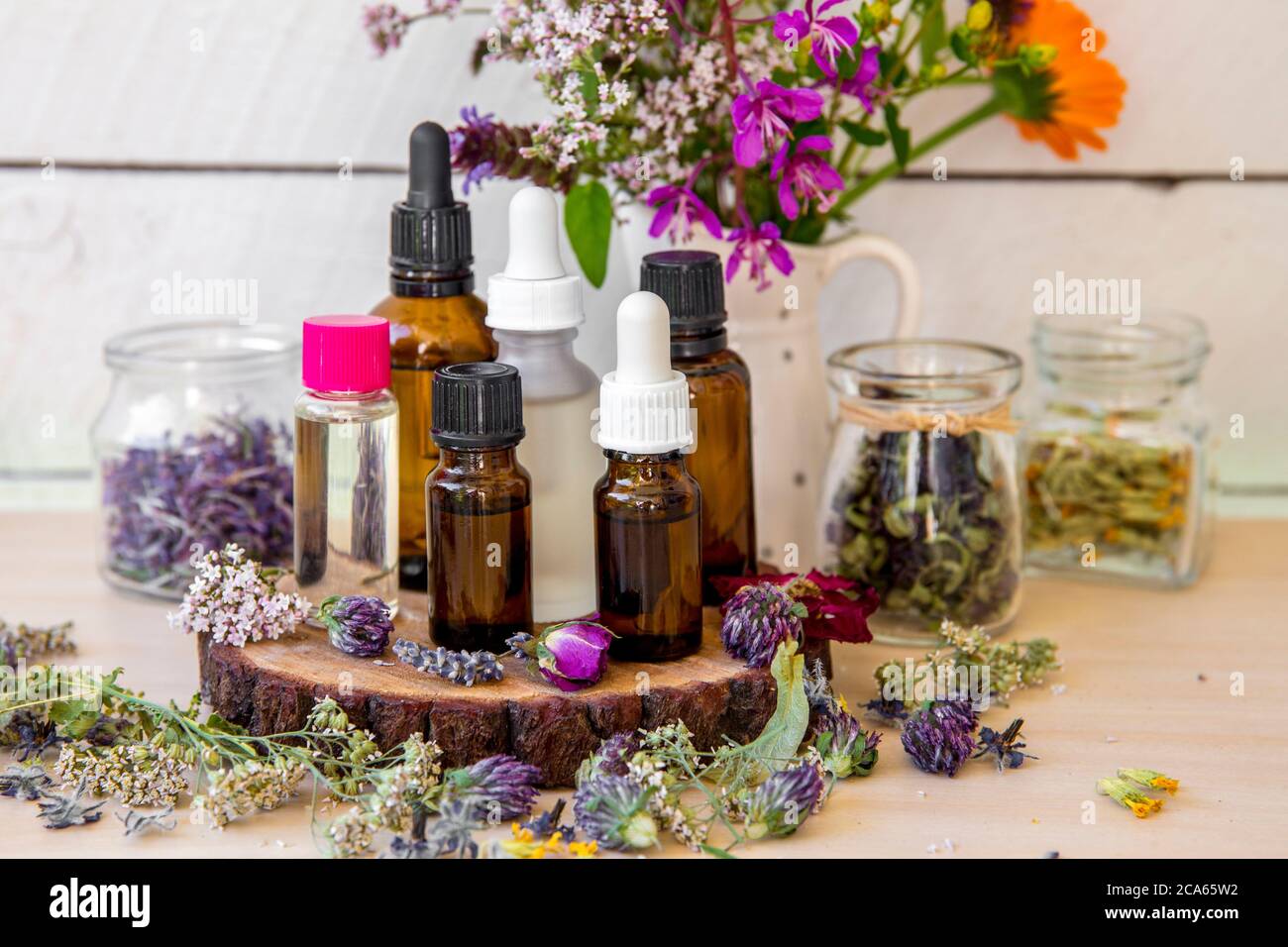 Viele verschiedene aromatische Ölflaschen auf dem Tisch, dekoriert mit wilden getrockneten Blumen und Pflanzen. Lifestyle-Komposition. Stockfoto
