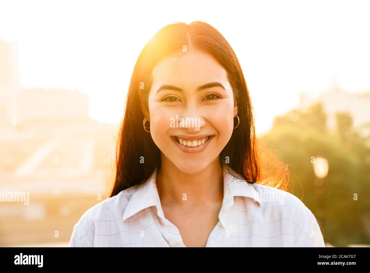 Foto von fröhlichen schönen asiatischen Frau lächeln und Blick auf die Kamera, während Sie im Freien zu Fuß Stockfoto