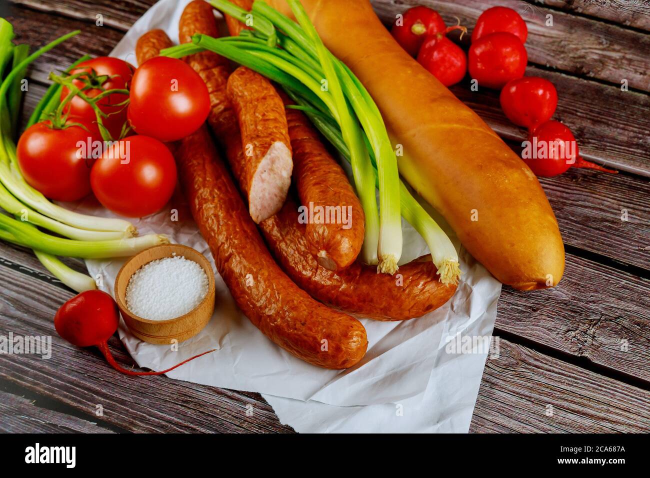 Klassische polnische Wurst mit Gemüse und Brot auf Holztisch. Stockfoto