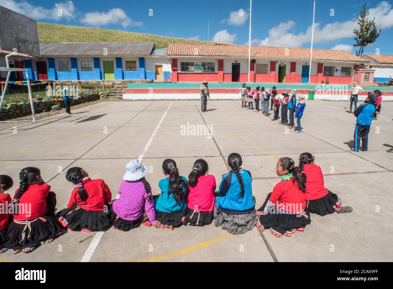 Quechua-Kinder in einer Andengemeinschaft versammeln sich draußen, um einem pädagogischen Sprecher in Peru zuzuhören. Stockfoto