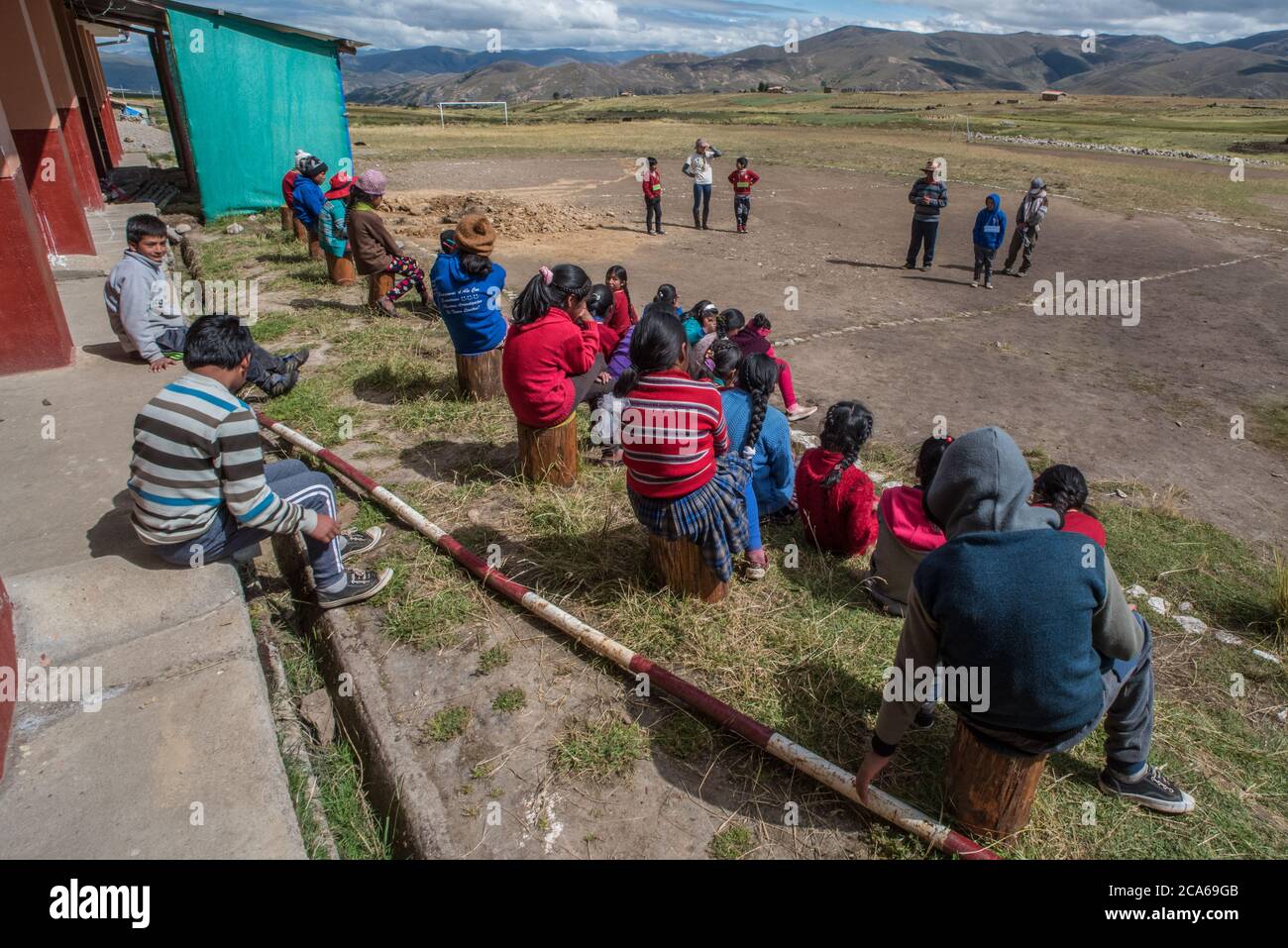 Quechua-Kinder in einer Andengemeinschaft versammeln sich draußen, um einem pädagogischen Sprecher in Peru zuzuhören. Stockfoto