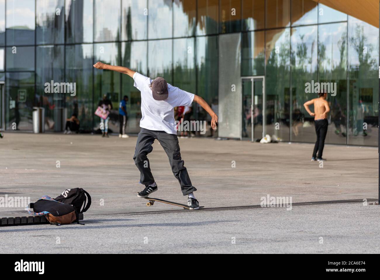 Junger Mann oder Teenager mitten in einem Skateboard-Trick vor der Central Library Oodi in Helsinki, Finnland Stockfoto