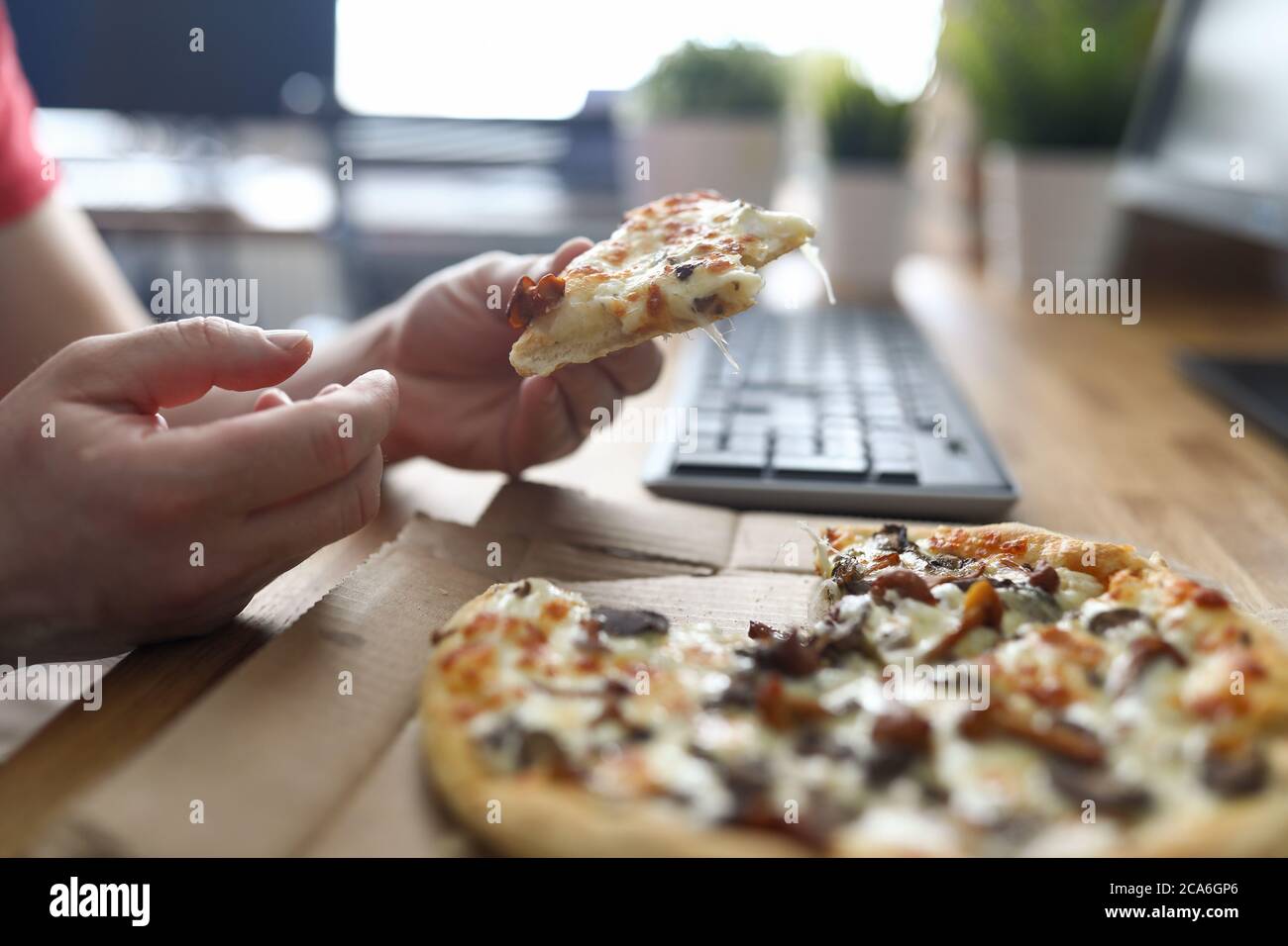 Mann, der Pizza am Arbeitsplatz vor dem Computer isst Stockfoto
