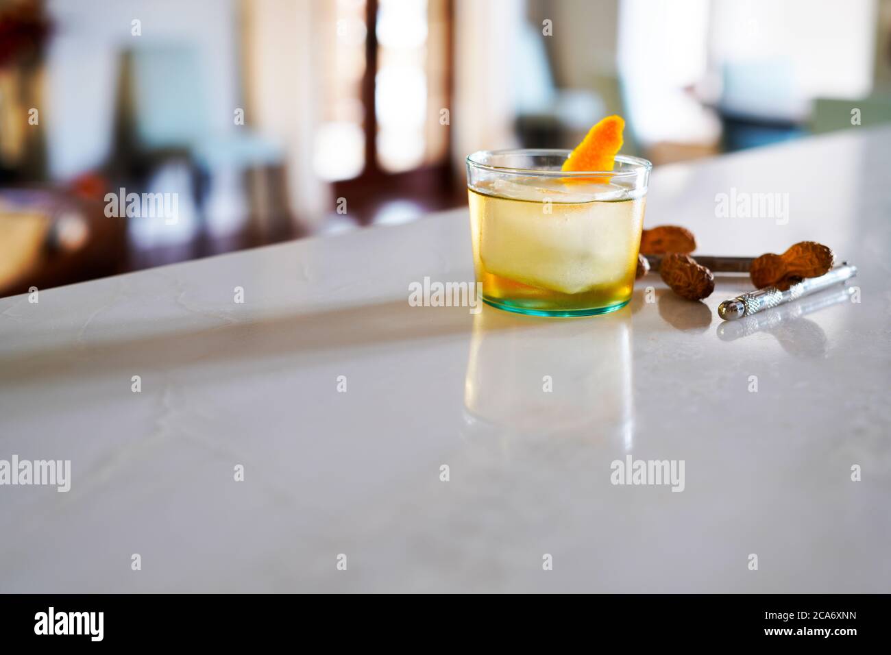 Tequila Old-Fashioned Cocktail mit einem orangen Twist und einer Begleitung von Erdnüssen Stockfoto