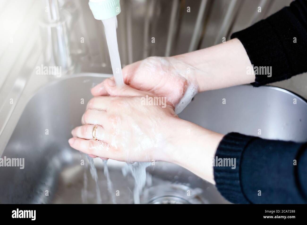 Eine junge kaukasische Frau spült ihre Hände nach dem Waschen mit Seife. Persönliche Hygiene und Virenprävention. Stockfoto
