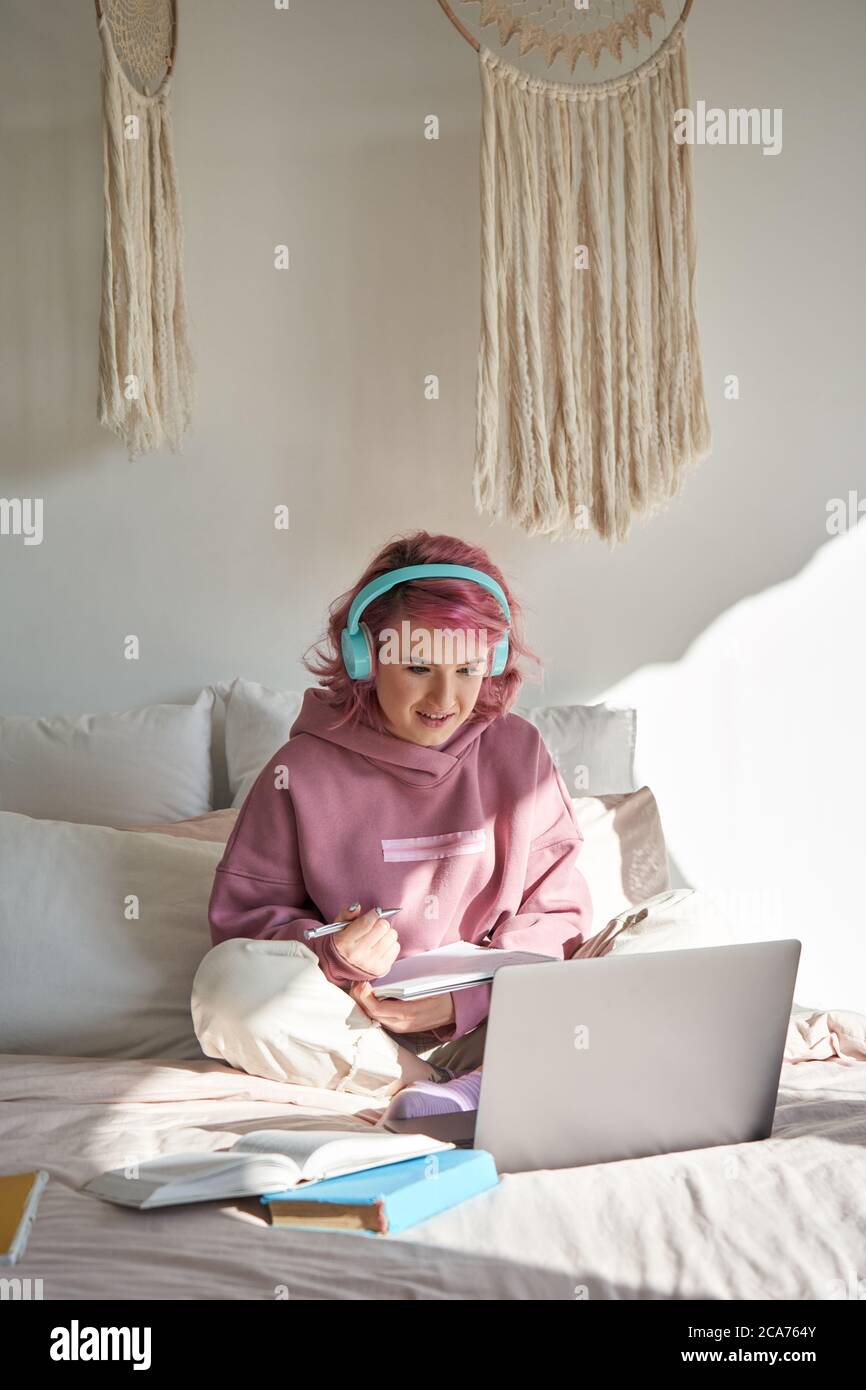 Teen girl gen z Student mit rosa Haar sehen online Webinar Lernen im Bett. Stockfoto