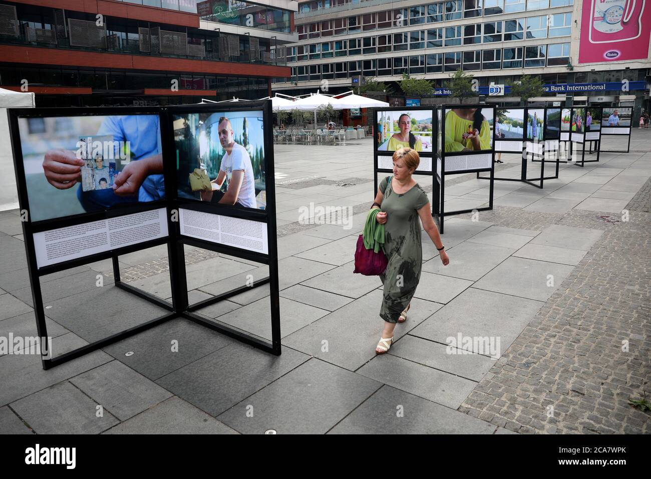 Sarajevo, Bosnien und Herzegowina (BiH). August 2020. Eine Frau kommt an der Ausstellung Kinder und Völkermord auf dem Kinderplatz in Sarajevo, Bosnien und Herzegowina (BiH), 4. August 2020 vorbei. Die Außenausstellung, die vom 31. Juli bis zum 6. August stattfindet, zeigt Porträts von Menschen und ihre persönlichen Geschichten, deren Kindheit vom Völkermord in Srebrenica geprägt war. Quelle: Nedim Grabovica/Xinhua/Alamy Live News Stockfoto