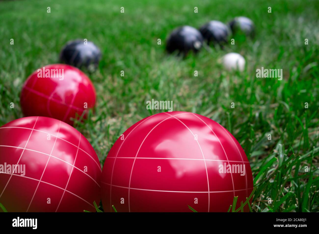 Rote und dunkelblaue Bocci Bälle auf einem grünen Rasen spielen das Spiel Stockfoto