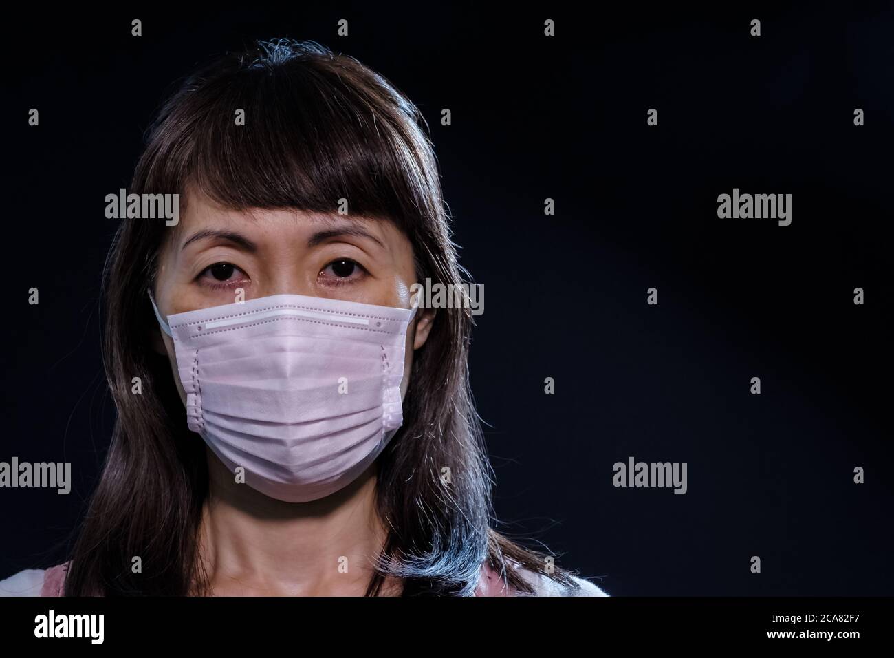 Japanische Mädchen in Maske vor schwarzem Hintergrund Stockfoto