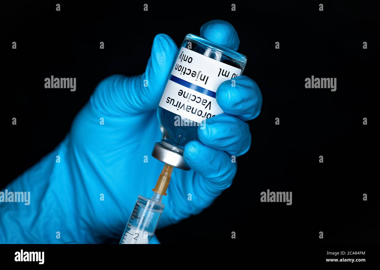 Hand in blauen Handschuhen mit hypodermischer Spritze und Coronavirus-Impfstoff (Aufkleber eigenes Design, nicht echtes Produkt), Injektion es Nahaufnahme Detail, schwarze Rückseite Stockfoto