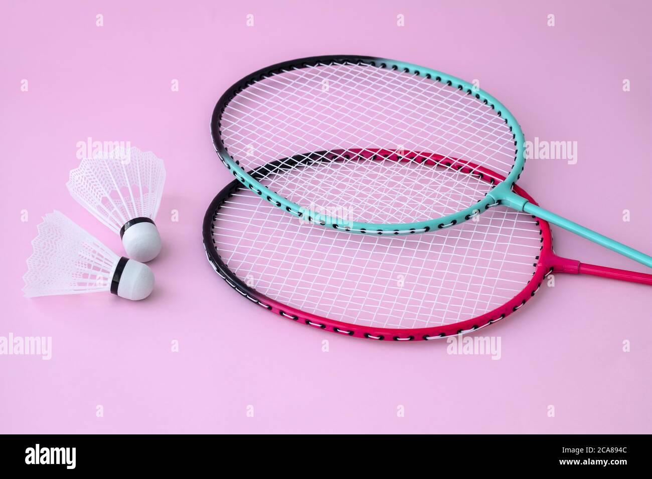 Zwei Badminton Schläger und Federball auf rosa Hintergrund. Flach liegend, Freizeitausrüstung. Sportspiel-Konzept Stockfoto