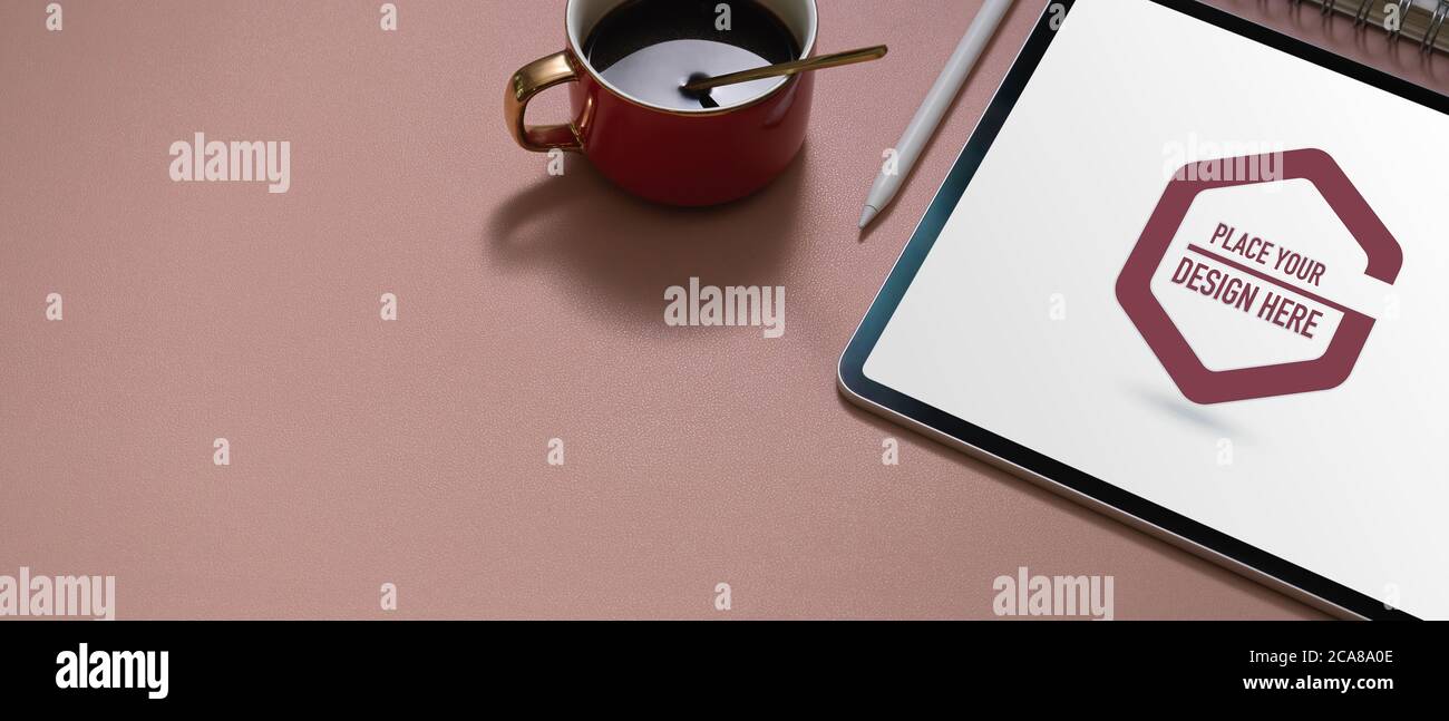 Abgeschnittene Aufnahme des Arbeitsbereichs mit Tablet-PC, Stylus, Kaffeetasse und Kopierfläche auf rosafarbenem Tisch Stockfoto