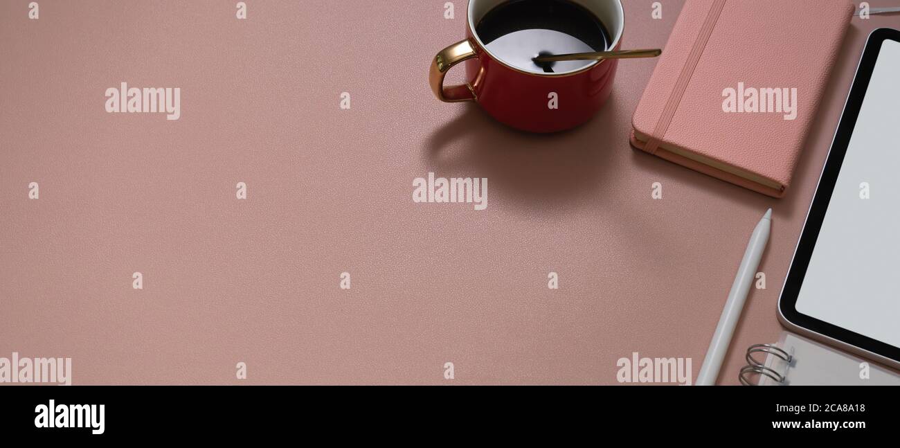 Draufsicht auf den Arbeitsbereich mit Kaffeetasse, Tablet-Modell, Schreibwaren und Kopierfläche auf pinkem Schreibtisch Stockfoto