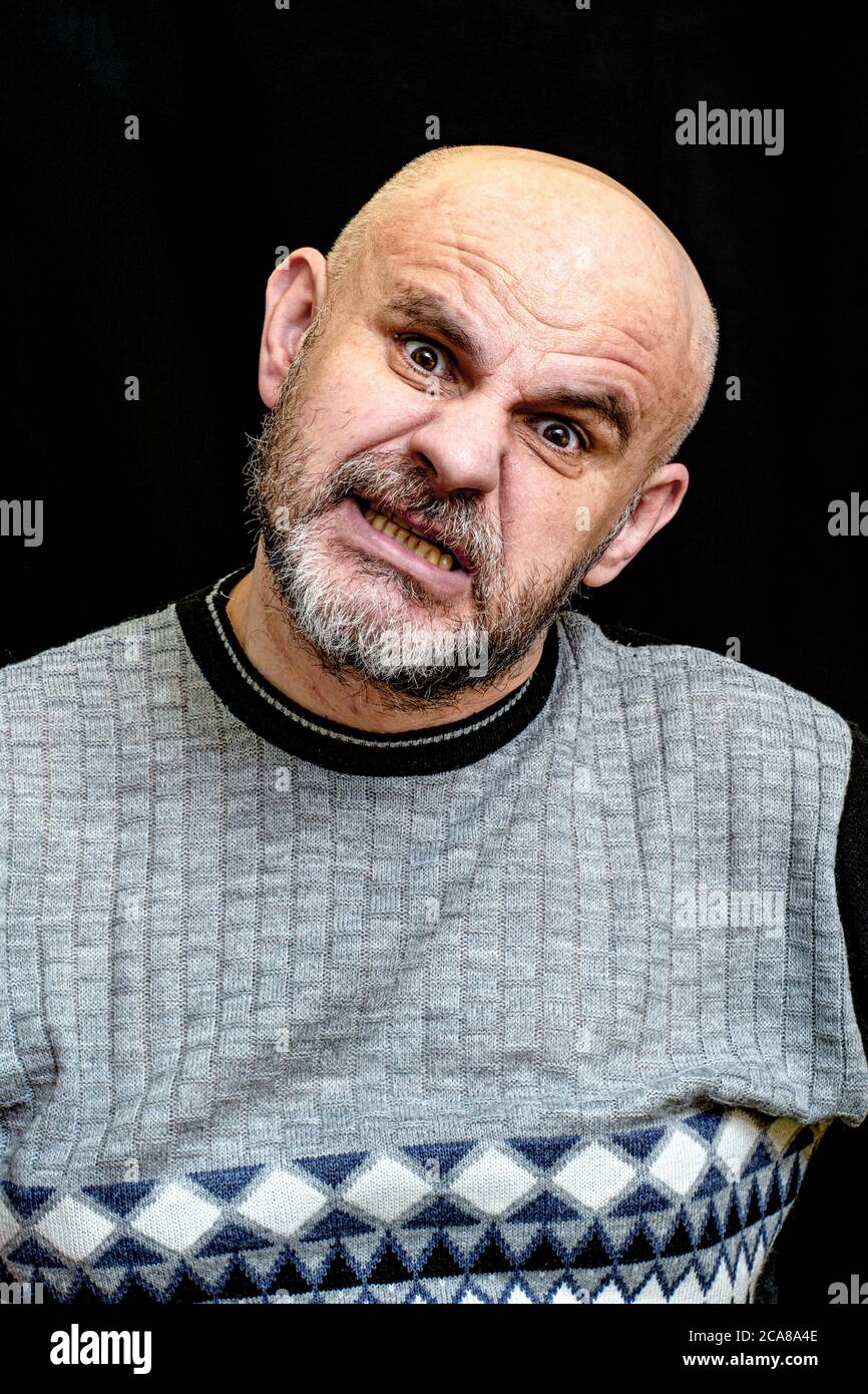 Kahler, bärtiger Mann mittleren Alters macht unheimlich Gesicht entblößt Zähne Stockfoto