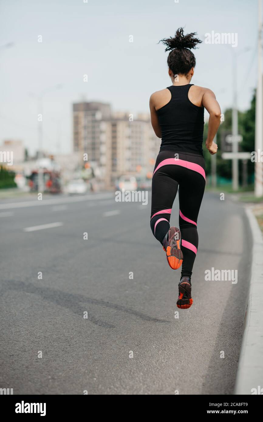 Morgen joggen auf der Straße in der Stadt. Muskulöse Mädchen in Sportbekleidung gefroren in der Luft, Joggen Stockfoto