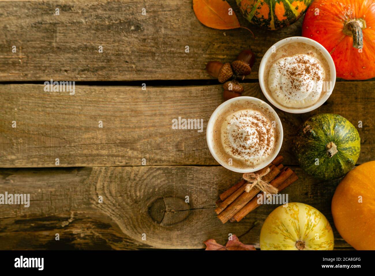 Kürbis gewürzter Latte in orangefarbenen Gläsern auf Holzhintergrund Stockfoto