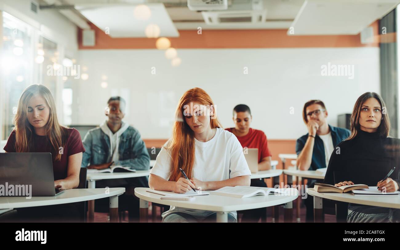 Männliche und weibliche Schüler sitzen im Klassenzimmer und machen Notizen während der Vorlesung. Schüler in der High School Klassenzimmer. Stockfoto