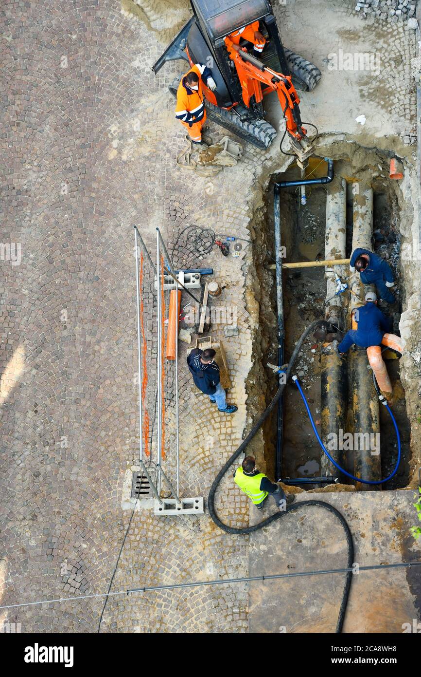 Luftaufnahme der Arbeiter Reparatur von Rohren in einer Ausgrabung unter der Straßenoberfläche, Alba, Cuneo, Piemont, Italien Stockfoto